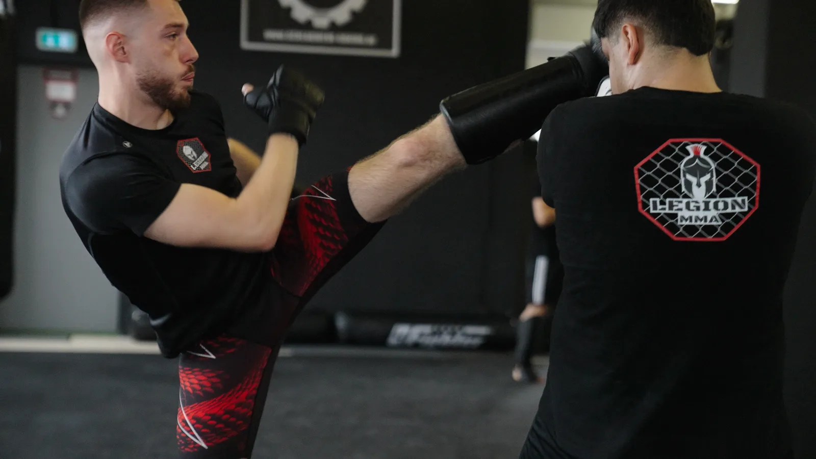 Kickboxer trifft mit dem Schienbein die Pratze des Trainers bei Legion MMA