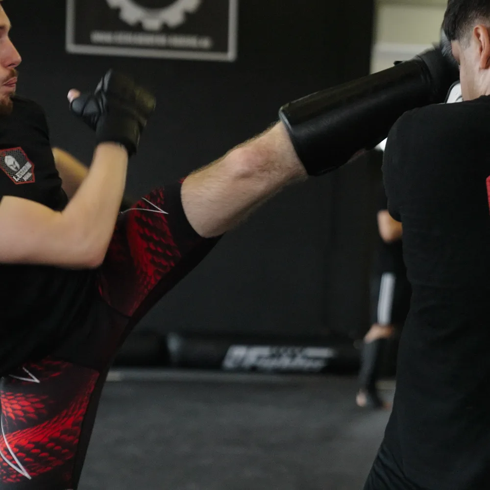 Kickboxer trifft mit dem Schienbein die Pratze des Trainers bei Legion MMA