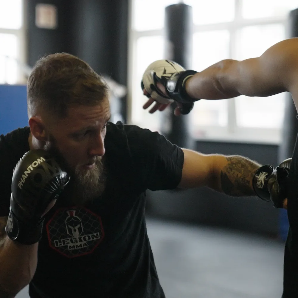 Trainer zeigt einen Cross mit MMA-Handschuhen