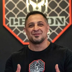 Arton Kasumaj, Striking-Coach und Krav-Maga-Instructor bei Legion MMA, vor dem Vereinslogo