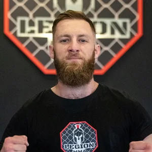 David Kodric, Headcoach und Gründer von Legion MMA, vor dem Vereinslogo